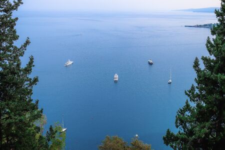 View of a blue sea with boats and frame treesの写真素材