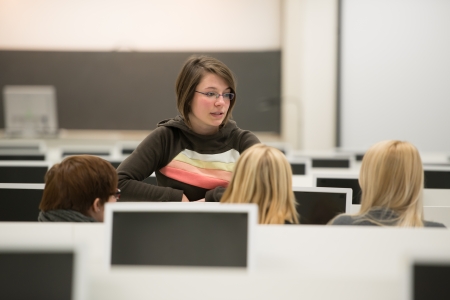 Four female students discussing in auditoriumの写真素材