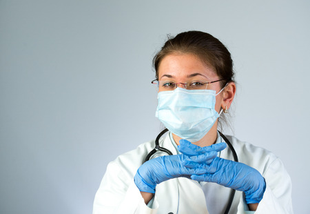 young female doctor wearing latex gloves, glasses and maskの写真素材