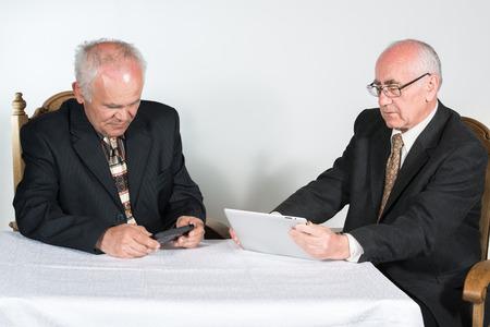 two senior businessmen,  using tablet and smatphoneの写真素材