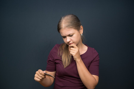 Thoughtful  young woman holding bank card, thinking low key, black backgroundの写真素材