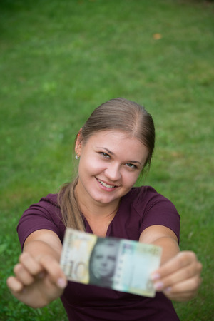 Young happy blonde woman holding Swiss franc banknote