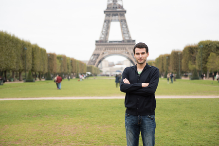 Young man standing in front of Eifel Tower in Paris, France, wearing black clothesの写真素材