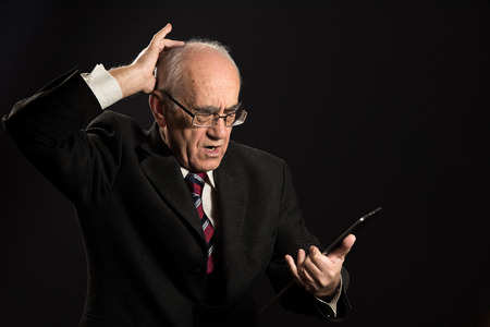 senior businessman works with tablet pc, in troubleの写真素材