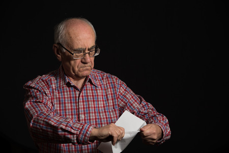 elderly man, wearing checked shirt reads bank document, final noticeの写真素材