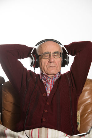 old seniour man wearing headphones and listening music wearing red sweaterの写真素材