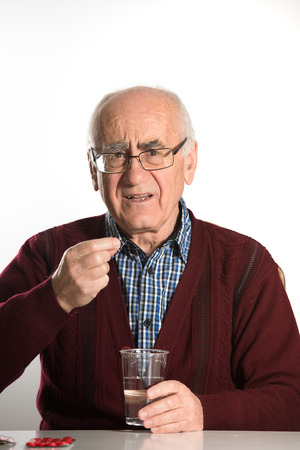 old senior man takes pills with water in plastic cupの写真素材