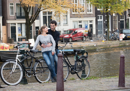 young couple, man and woman in Amsterdam, Netherlands, on the side of canal with bicyclesの写真素材