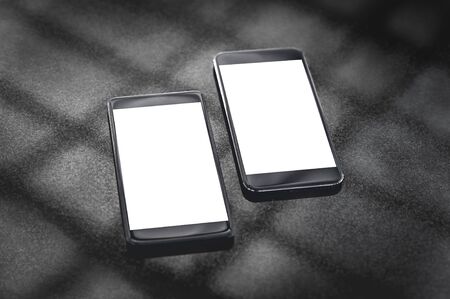 Mock up of black smartphones on a gray background with the shadow of the lattice.の写真素材