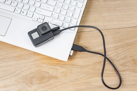 Action camera connected to a white laptop, against the background of a wooden table.の写真素材