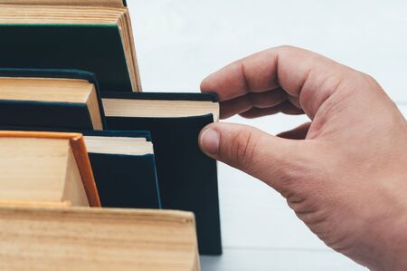 Hand pulls a book, from the bookcase.の写真素材