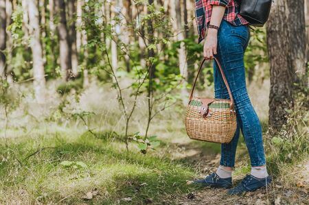 A girl with a basket in hand walks through the woods. Concept on the theme of outdoor recreationの写真素材