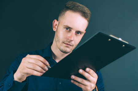 Businessman with a folder for documents in his hands, on a black backgroundの写真素材