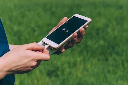 The girl cuts the phone from the bank. in field