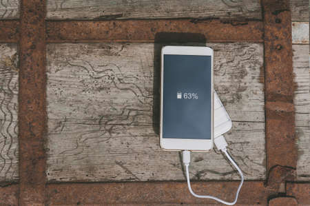 Close-up of charging the phone from the power bank. On an old wooden chestの写真素材