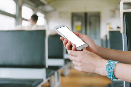 Mock up of a smartphone, close-up in a female hand. Against the background of a train carriage