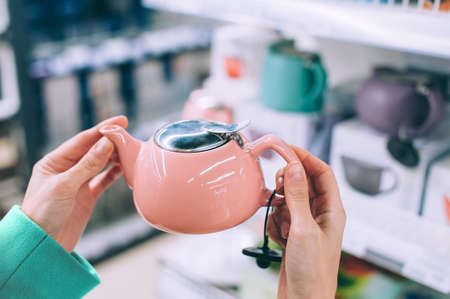 Close-up. Girl holds a kettle in her hands in a supermarket
