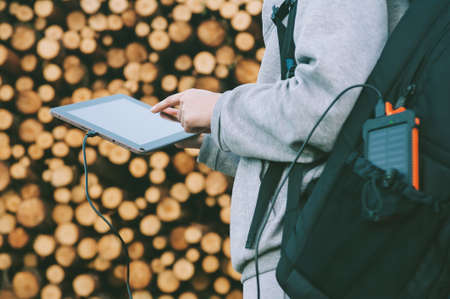 Powerbank in a backpack pocket. Against the background of a girl with a finger near the screen of...
