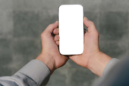 Close up, mock up smartphone, in hands, of a person. against the background of a concrete wallの写真素材