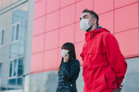 A man and a girl in a medical mask stand at a distance in the background of the cityの写真素材