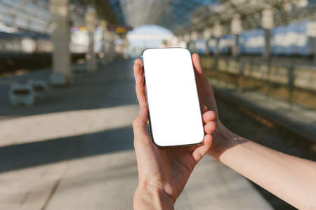 Mock up of a smartphone in the hands of a girl at the stationの写真素材
