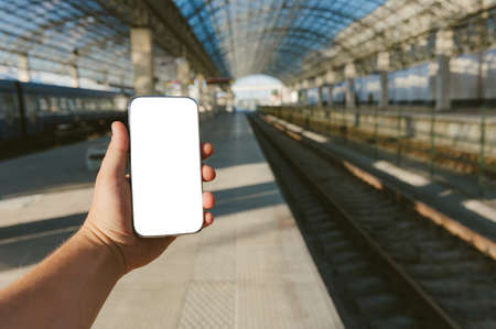 Mock up of a smartphone in the hand of a man at the train stationの写真素材