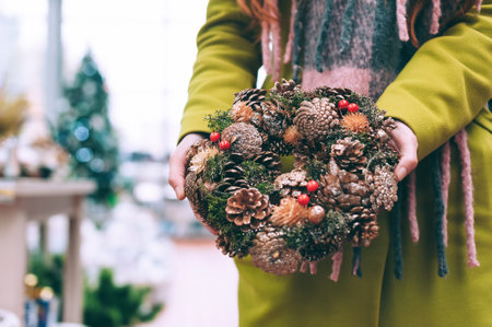 The girl holds in her hands New Year's, Christmas wreath of decorative ornaments for the home. Against the background of a veteran workshopの写真素材