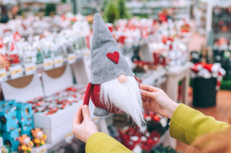 The girl holds Tomte in her hands. against the background of the counter of the Christmas New Year's shopの写真素材