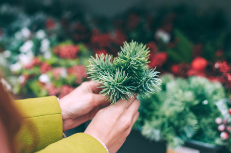 A girl holds a fir branch in her hands for decoration for Christmas and New Year. Against the background of the store counterの写真素材