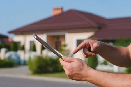 Finger in front of the Tablet on the background of the houseの写真素材