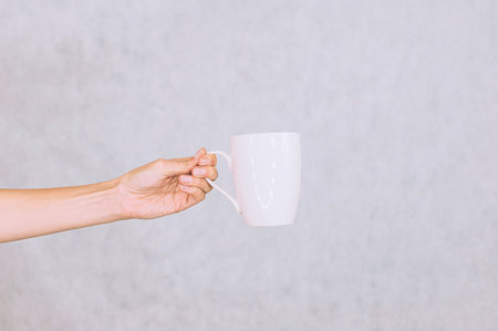White mug for coffee, tea in the girl's hand. On a white backgroundの写真素材