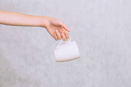 White mug for coffee, tea in the girl's hand. On a white backgroundの写真素材