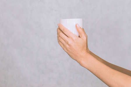 White mug for coffee, tea in the hands of a girl. On a white backgroundの写真素材