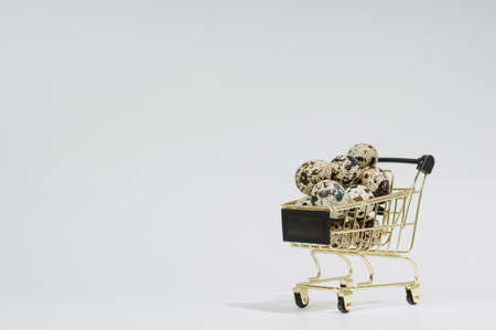 Close-up of quail eggs in a cart. On a light background. Easter and egg sale concept