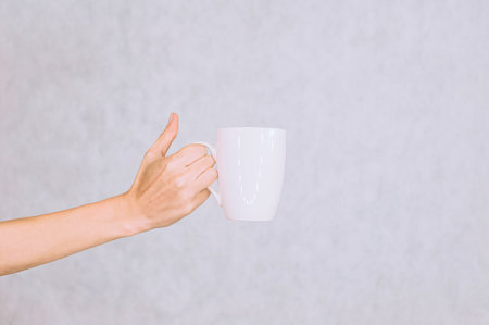 White mug for coffee, tea in the girl's hand. On a white backgroundの写真素材