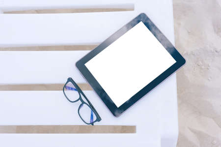 Close-up Mock up tablet on a sun lounger. Against the background of sand. Beach vacation conceptの写真素材