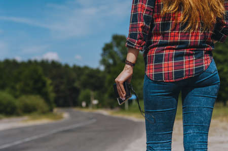 Power bank with a phone in the girl's hand. Against the background of the roadの写真素材