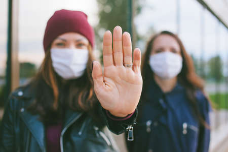 Hand on camera close-up, Female in medical masks. Against the backdrop of a glass building. Virus stop conceptの写真素材