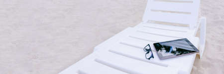 Banner, The mock-up of the tablet lies on a sun lounger. Against the backdrop of beach sand. Vacation conceptの写真素材