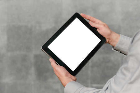 Close up, mock up tablet, in hands, of a person. against the background of a concrete wall