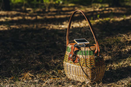 Mock up of a smartphone with charging Power Bank on a basket in the forest. Concept on the theme of outdoor recreationの写真素材