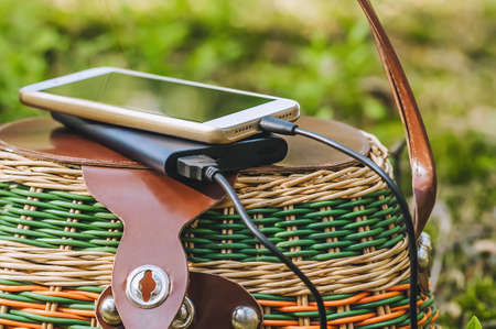 Mock up of a smartphone with charging Power Bank on a basket in the forest. Concept on the theme of outdoor recreationの写真素材