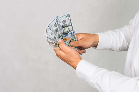 The money is in the hands of a man. On a light background
