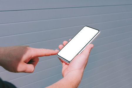 Close-up, Finger in front of the screen Mockup smartphone in the hands of a man. against the background of a gray wallの写真素材