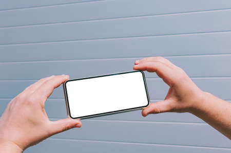 Close-up, mock-up of a smartphone in the hands of a man. against the background of a gray wall