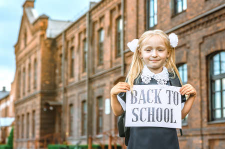 Portrait of schoolgirls with sign in hands with words back to school. Against the background of an...