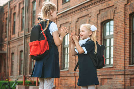 Two great Schoolgirls give each other five. First day of study. Concept on the topic Back to Schoolの写真素材
