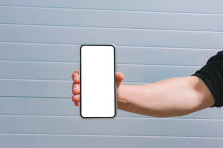 Mock up of a smartphone in a man's hand. against the background of a gray wallの写真素材