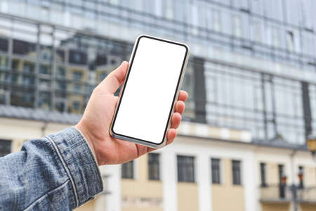 Smartphone mockup in the hands of a man. Against the backdrop of a glass business centerの写真素材