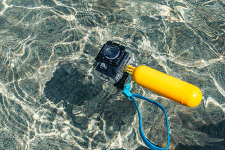 Waterproof action camera with a yellow float in the water on the waves of the pool